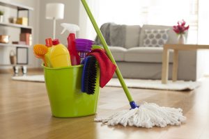 Plastic bucket with cleaning supplies in home